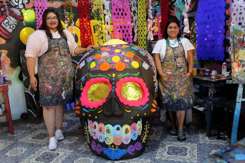 Dos integrantes de la Academia de Artes Yadarte posan junto a la calavera monumental terminada.