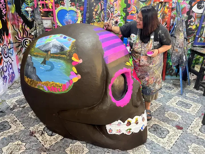 Detalle de una calavera monumental intervenida por la Academia Yadarte, con un paisaje pintado en la frente.