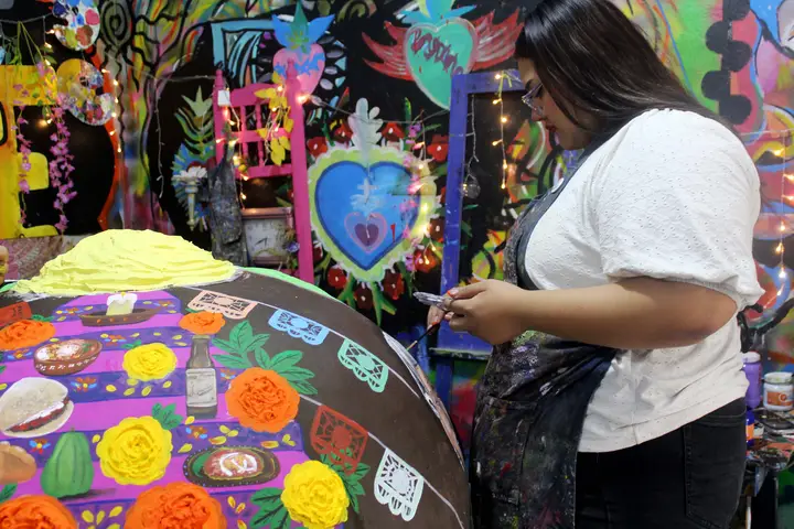Artista de Yadarte detalla flores y pétalos sobre la superficie de la calavera.