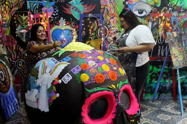 Integrantes de la academia trabajan simultáneamente en la pintura de la calavera monumental.