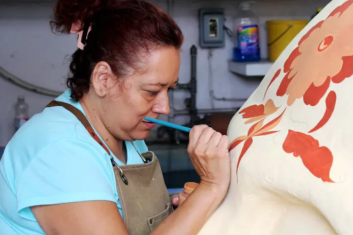 Irma Rosa Alavez Castillo detalla una flor de cempasúchil sobre la superficie.