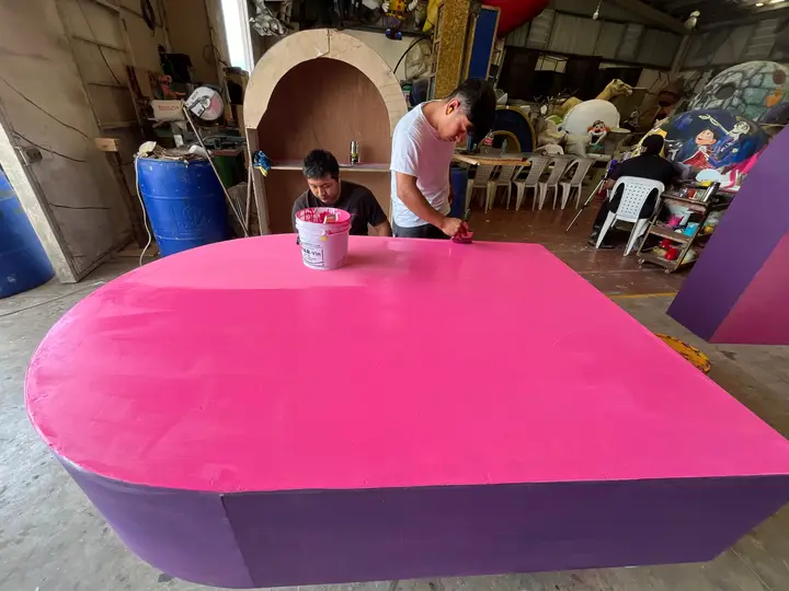 Aplicación de pintura rosa sobre una pieza de gran formato.