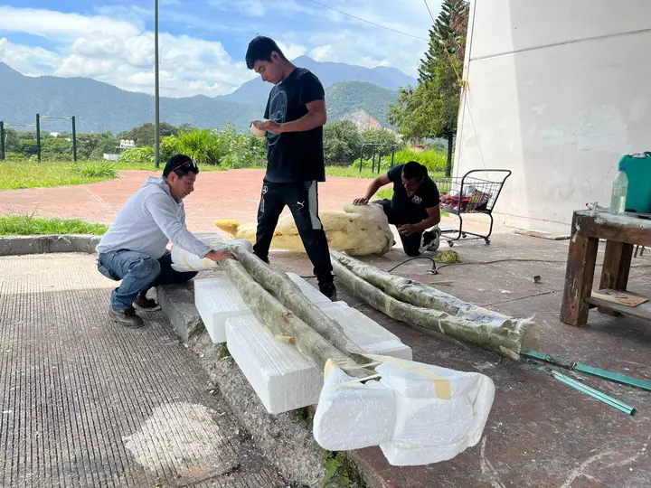 Equipo trasladando y armando piezas escultóricas al aire libre.