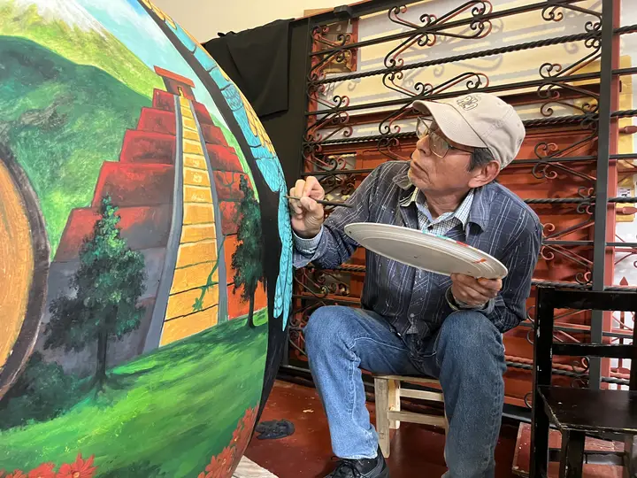 Artista del Jardín del Arte pinta una pirámide sobre la calavera monumental.